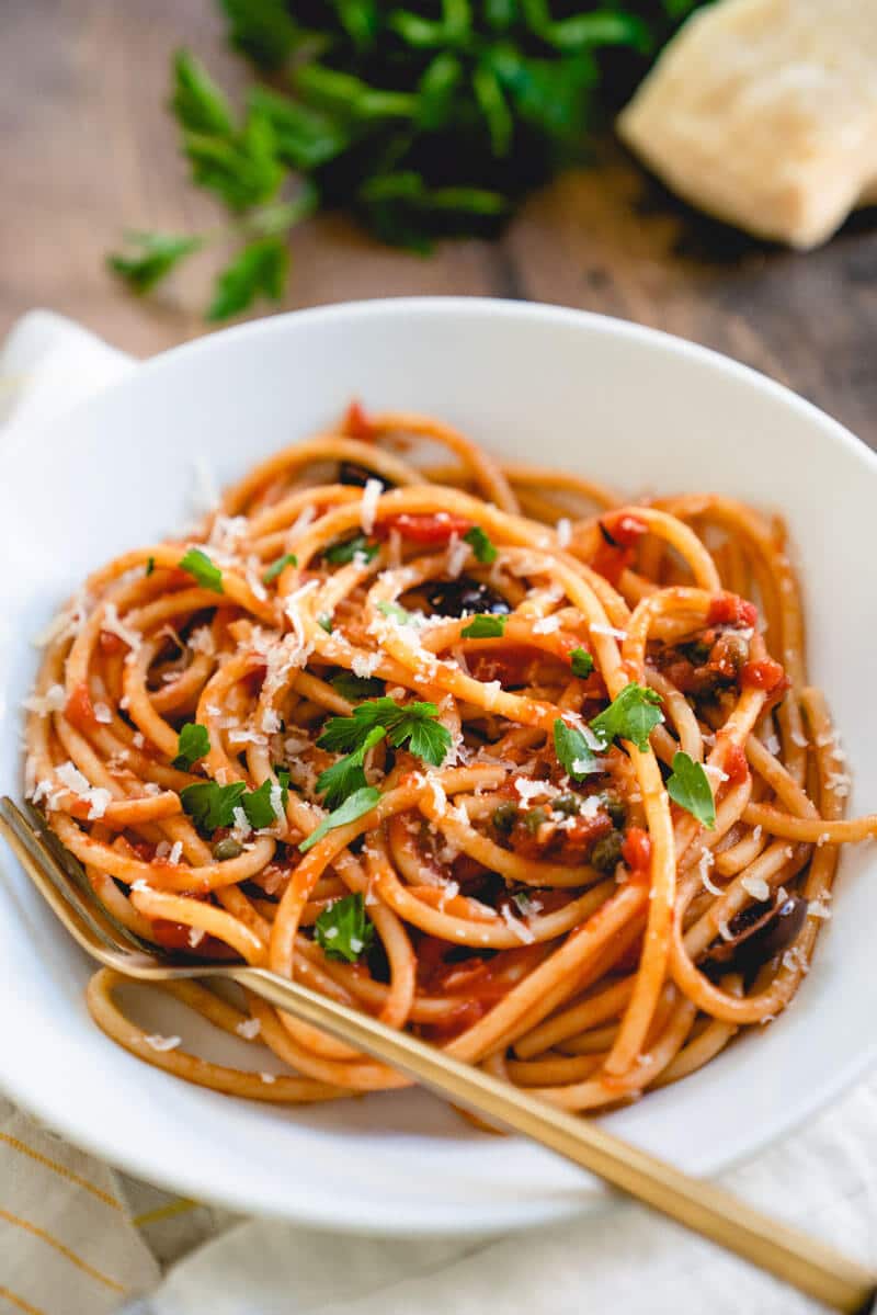 pasta puttanesca in white bowl with fork