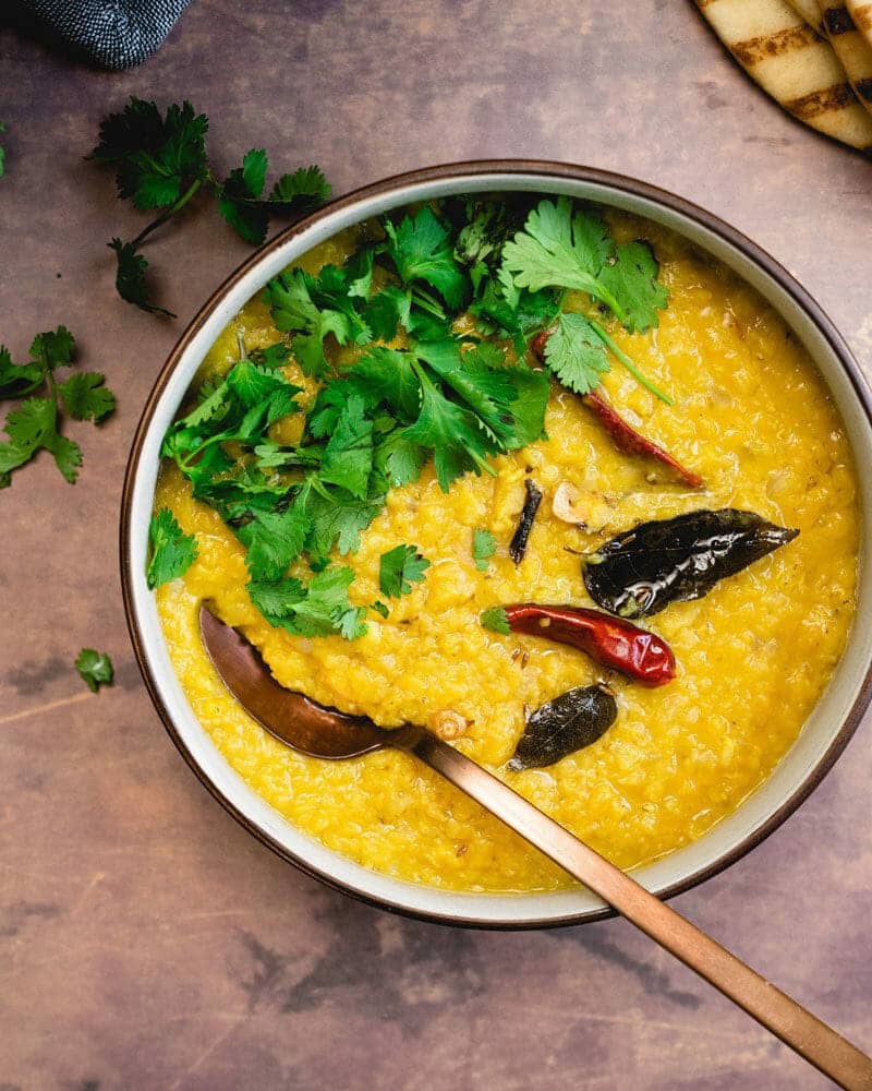 Masoor dal in a bowl, garnished with curry leaves and another leafy green