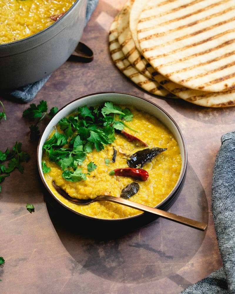 Masoor dal in a bowl, garnished with curry leaves and another leafy green 