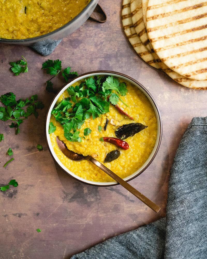 Masoor dal in a bowl, garnished with curry leaves and another leafy green