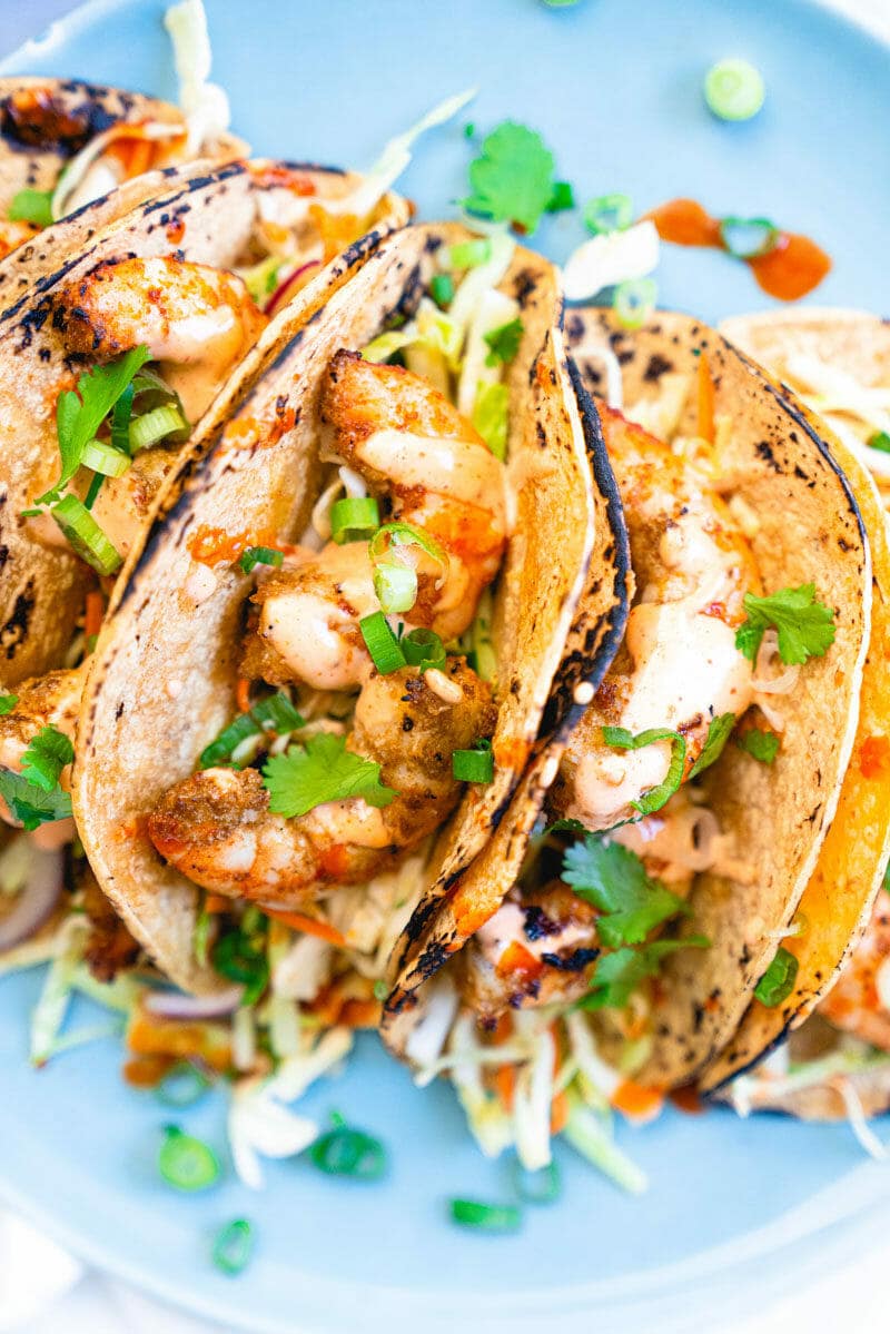 Three grilled shrimp tacos garnished with cilantro