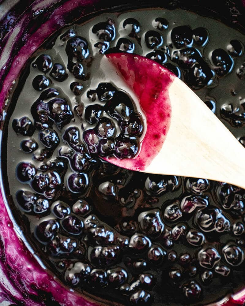 White spoon dipping into blueberry sauce