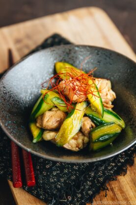 A black ceramic bowl containing Cucumber and Chicken Marinated in Chili Oil.