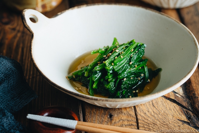 Spinach ohitashi in white ceramic plates.