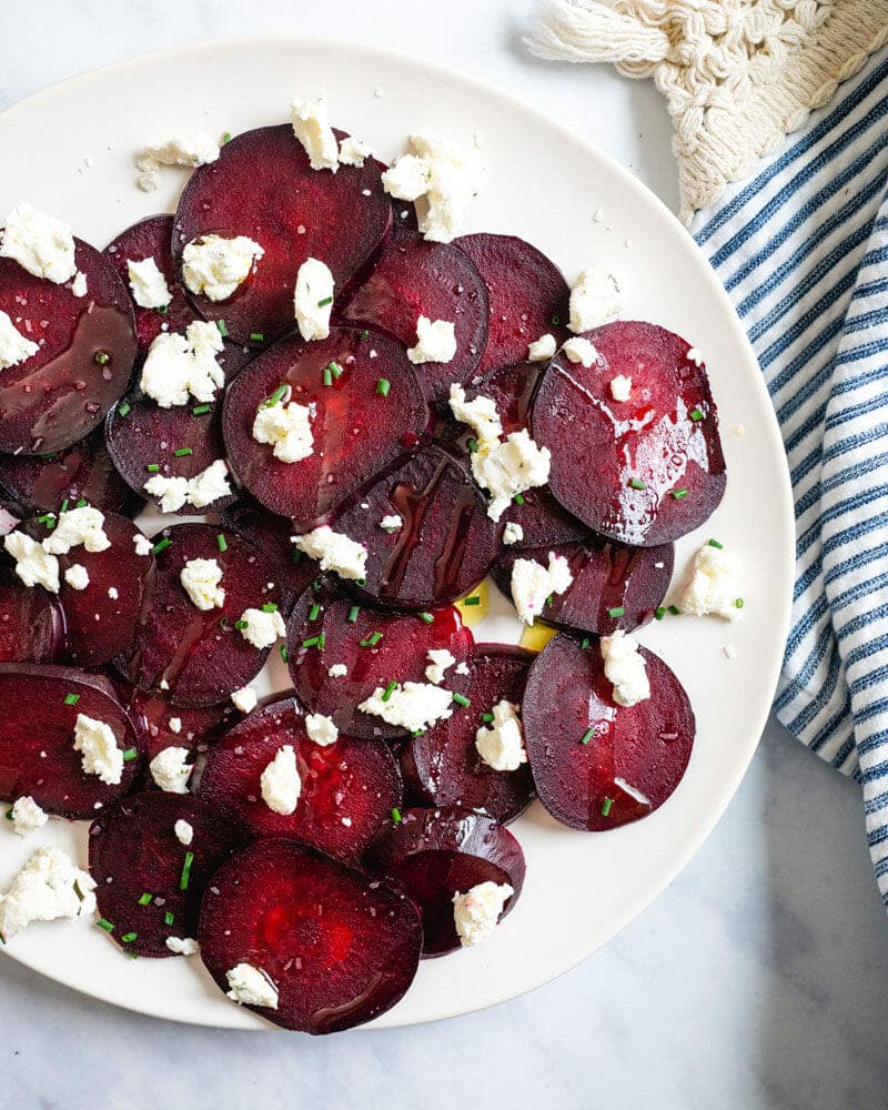 Roasted beets with goat cheese on a plate and drizzled with oil