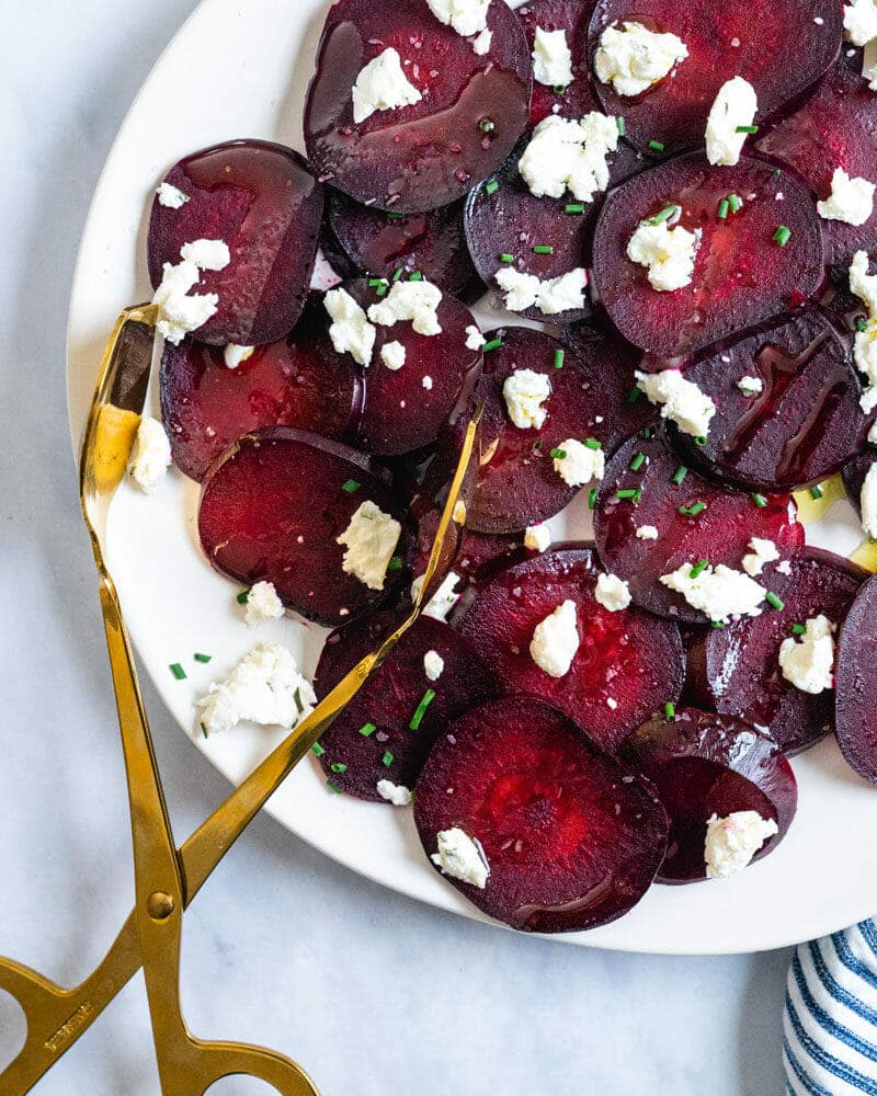 Roasted beets with goat cheese on a plate with tongs