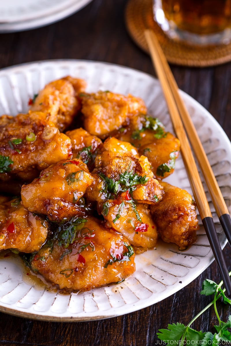 A white plate containing Chicken Karaage with Sweet Chili Sauce and cilantro garnish.