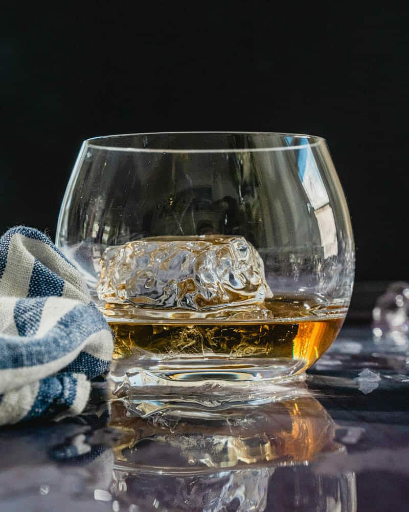 A round cup with dark liquor and clear ice