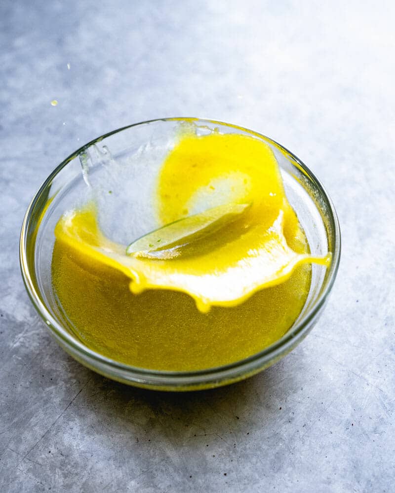 Lime dressing with a lime slice being dropped into the bowl, causing a splash