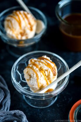 A glass bowl containing Soy Sauce Caramel Ice Cream topped with a drizzle of extra caramel.