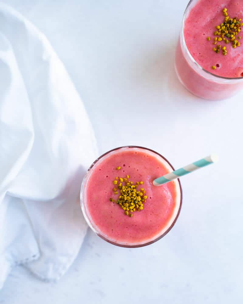 Almond milk smoothie with strawberries and banana in glass with straw