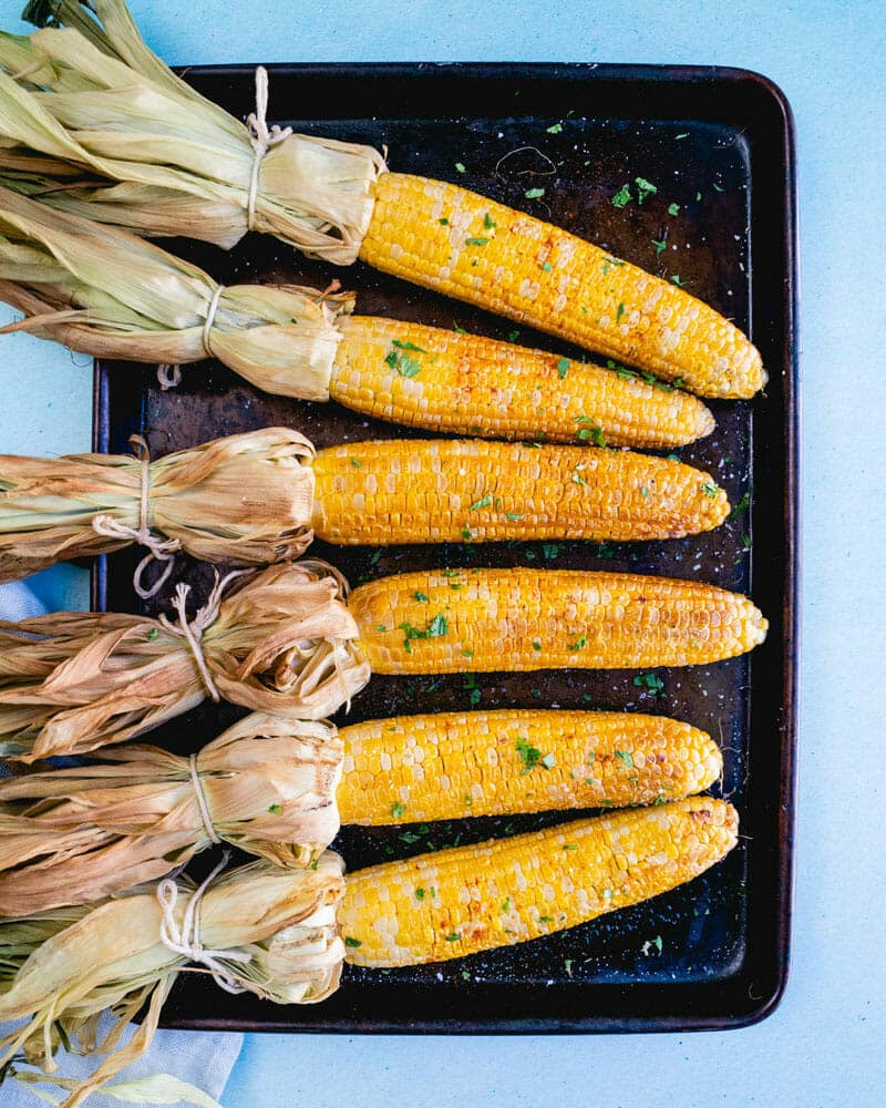 Smoked corn on the cob lined up on a tray