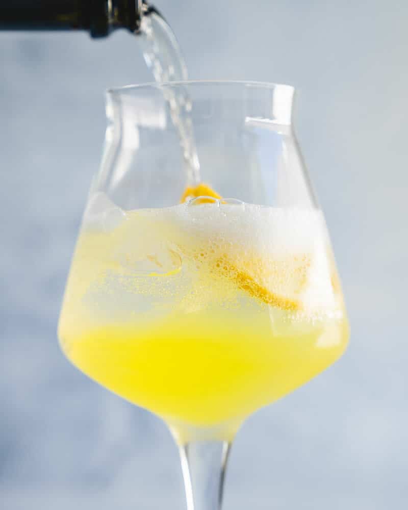 Limoncello spritz in a stemmed glass with Limoncello being poured in