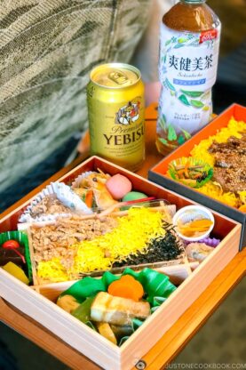 two bento boxes on a train table next to a beer can