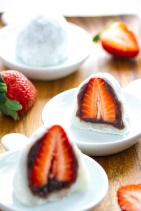 White plates containing strawberry mochi cut in half.