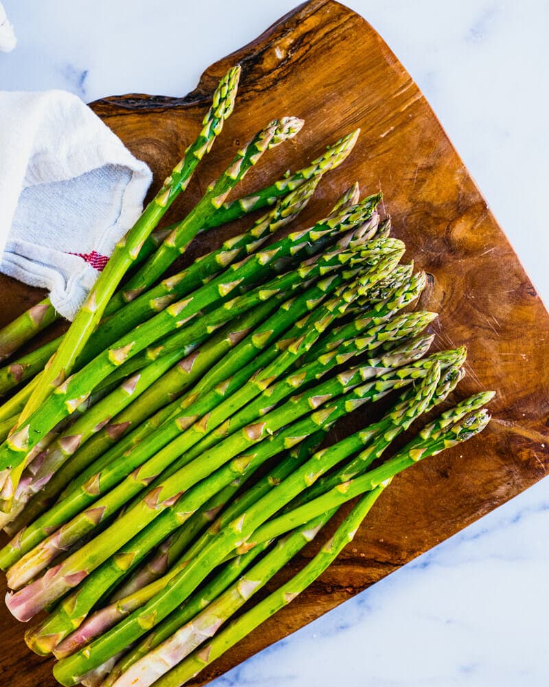 Asparagus lined up on a cutting board