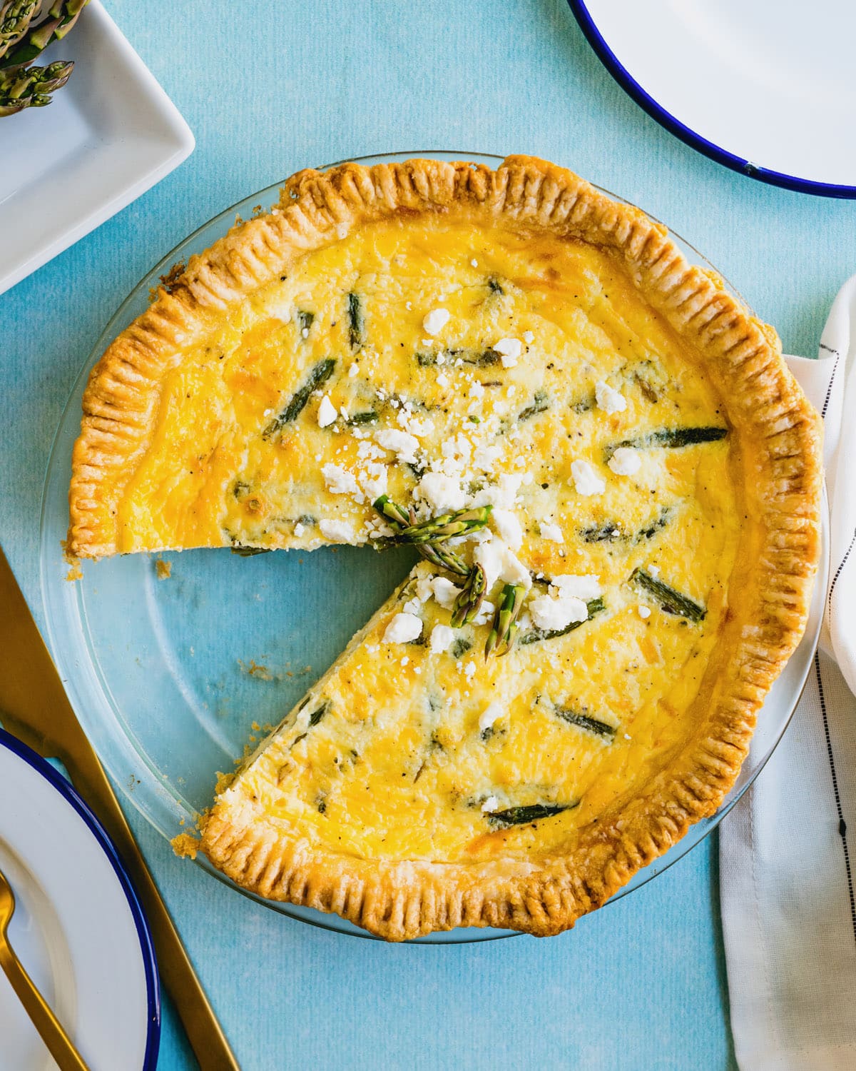 Asparagus Quiche in pie pan with feta cheese garnish.