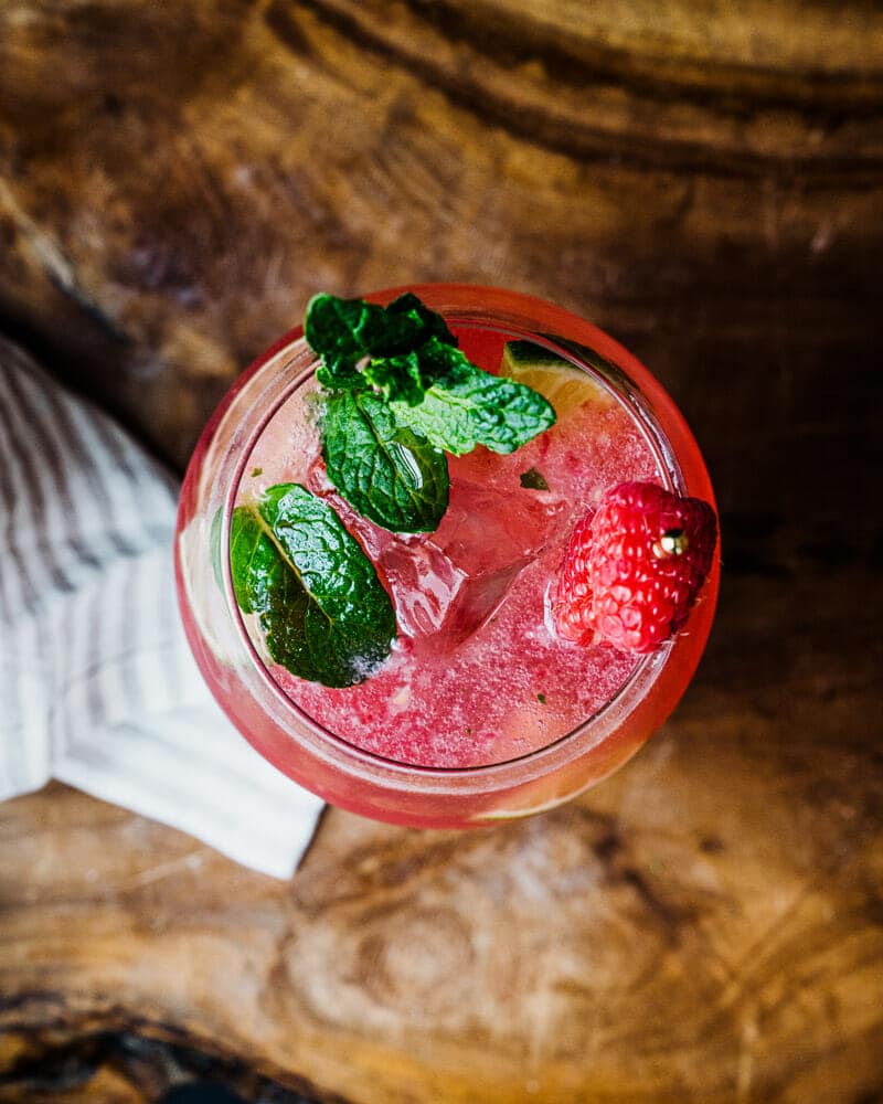 Raspberry mojito top view in a glass with raspberries, mint, and lime garnish