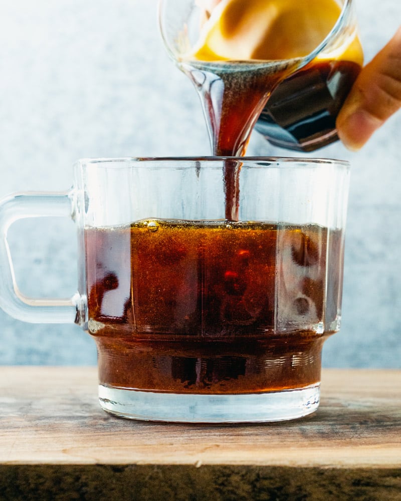 Red Eye Coffee in a short glass with a handle and espresso being poured in