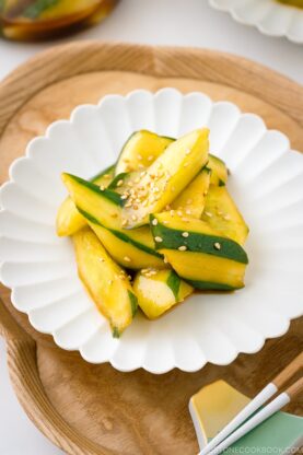 A white plate containing Spicy Japanese Pickled Cucumbers sprinkled with white sesame seeds.