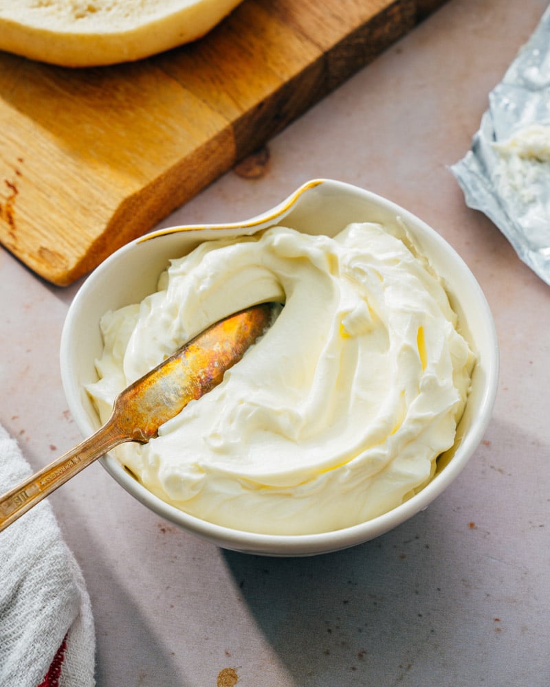 Whipped cream cheese in a uniquely shaped bowl, with a spreading knife dipped into it
