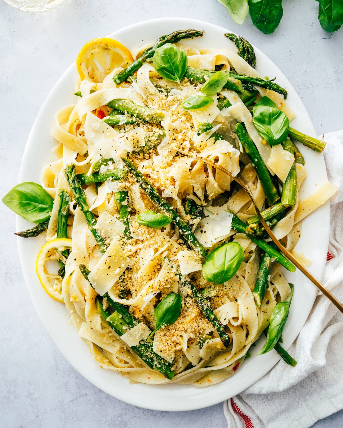 Asparagus pasta topped with Parmesan shavings and garnished with lemon and basil. 