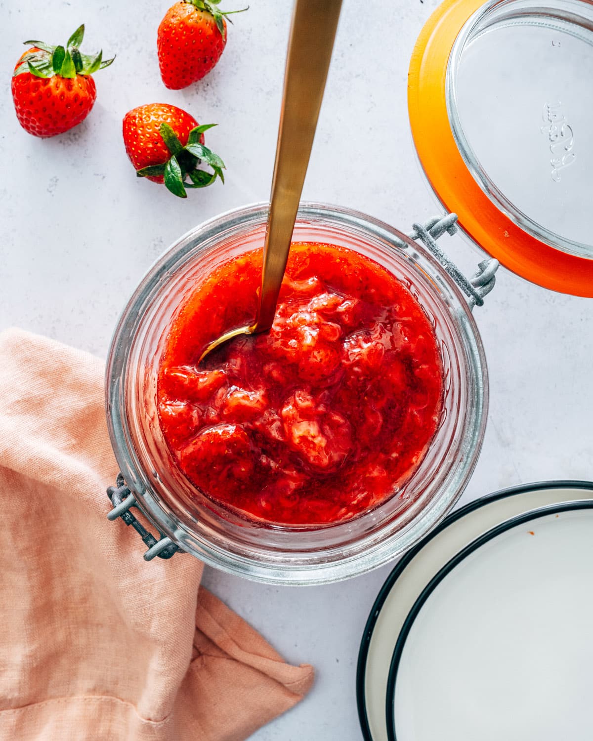 Strawberry Compote in jar with spoon and strawberries.