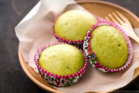 A wooden plate containing matcha green tea steamed cakes.