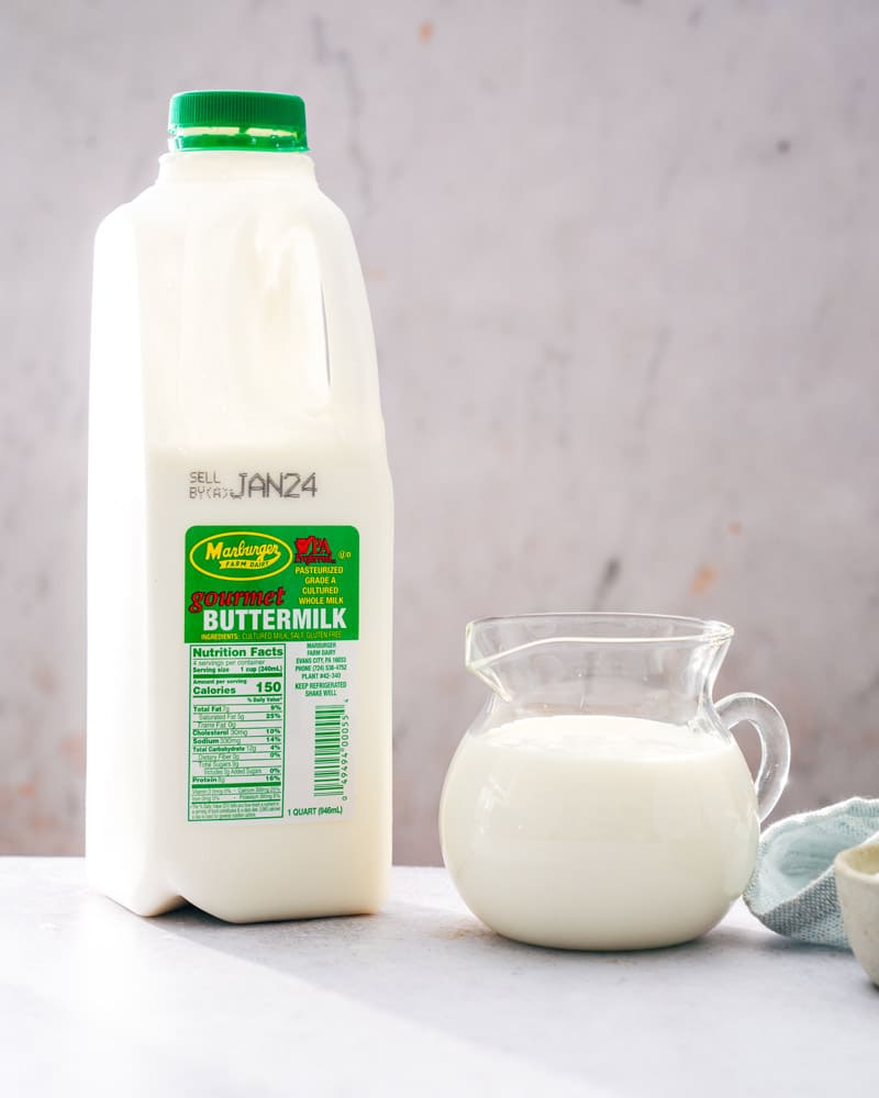 A quart jug of gourmet buttermilk next to a pitcher filled with buttermilk