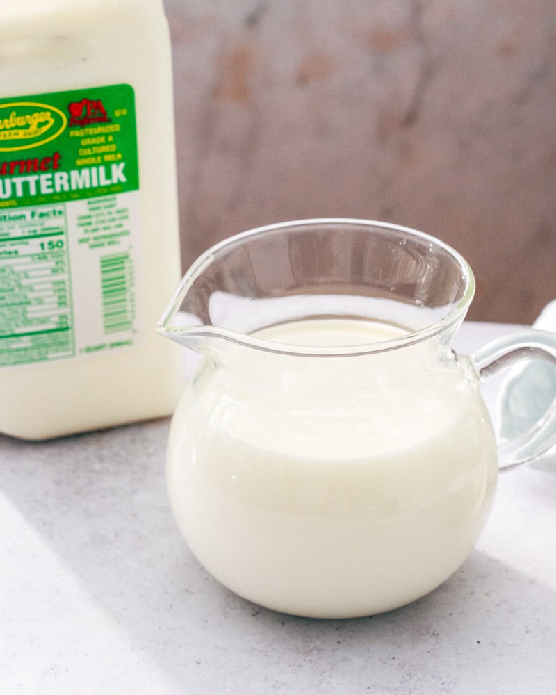 A quart jug of gourmet buttermilk next to a pitcher filled with buttermilk
