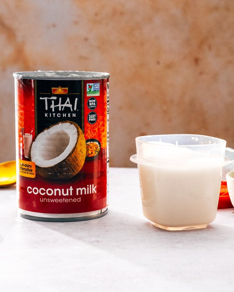 A can of Thai Kitchen coconut milk next to a small container full of milk