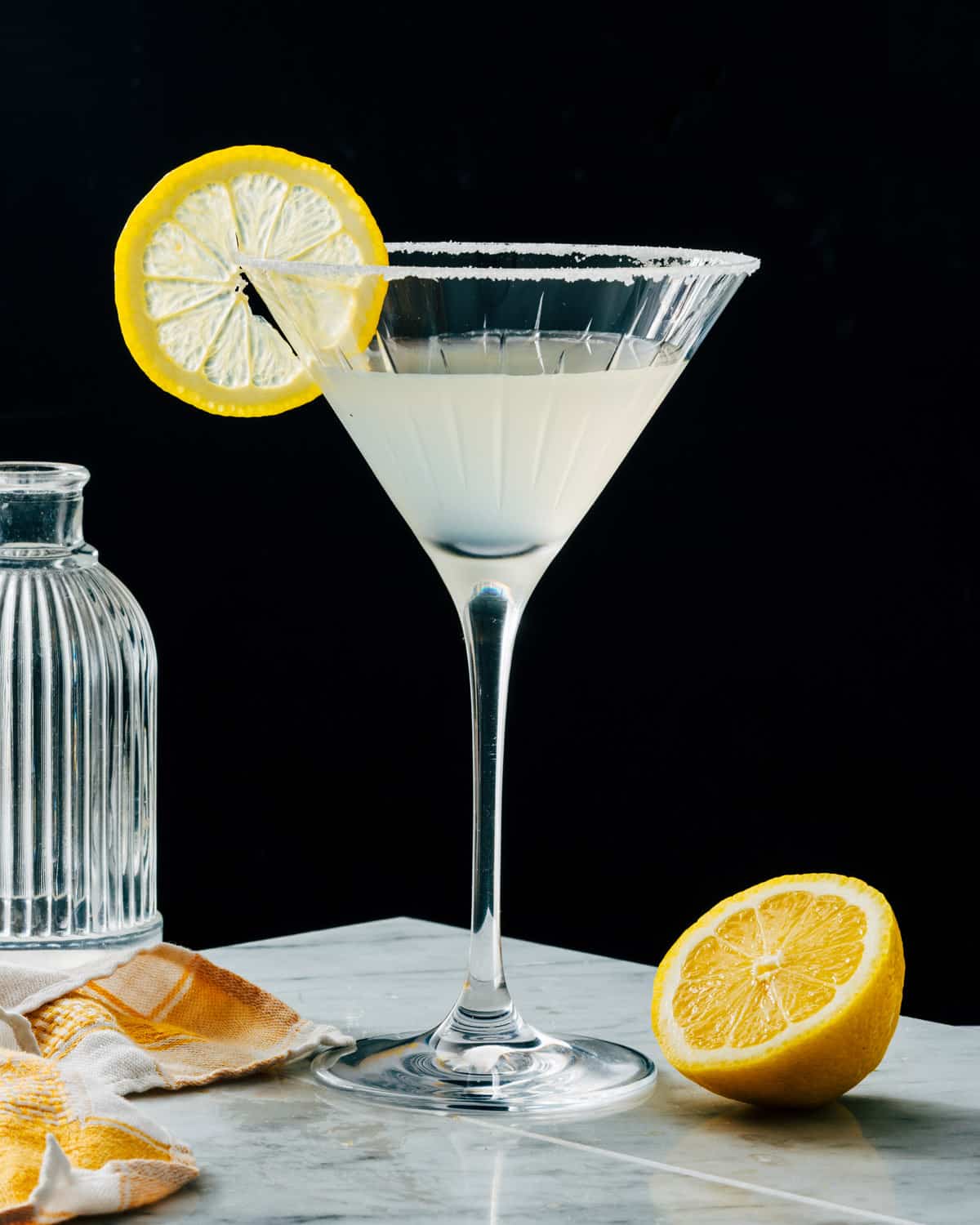 Lemon drop martini in martini glass with lemon garnish and sugar rim.