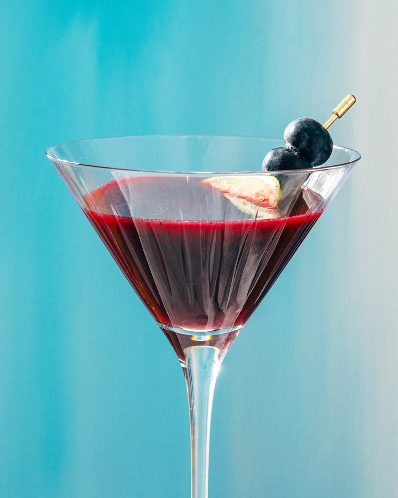 Blueberry Martini in a cocktail glass and garnished with blueberry and lime