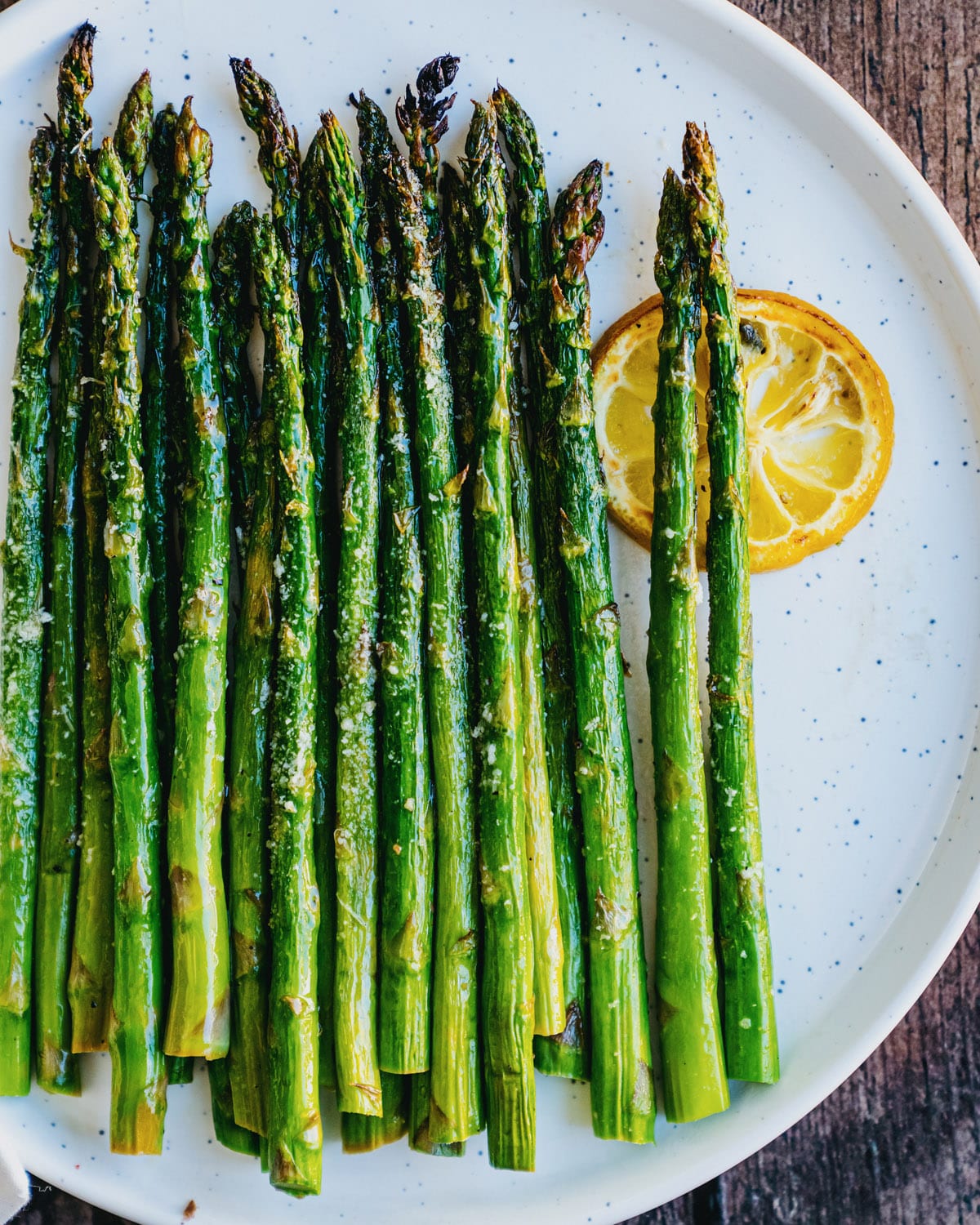 Broiled Asparagus recipe with spears on a plate with lemon slice.