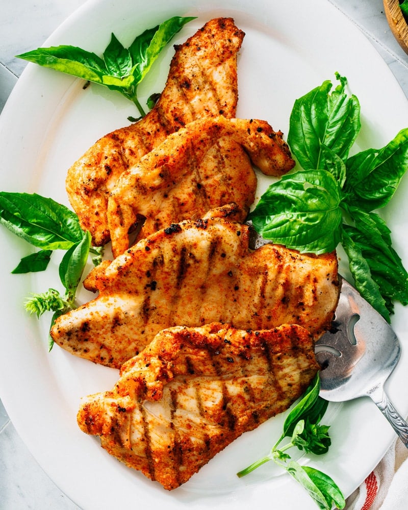Grilled Chicken Breast on platter with basil leaves. 