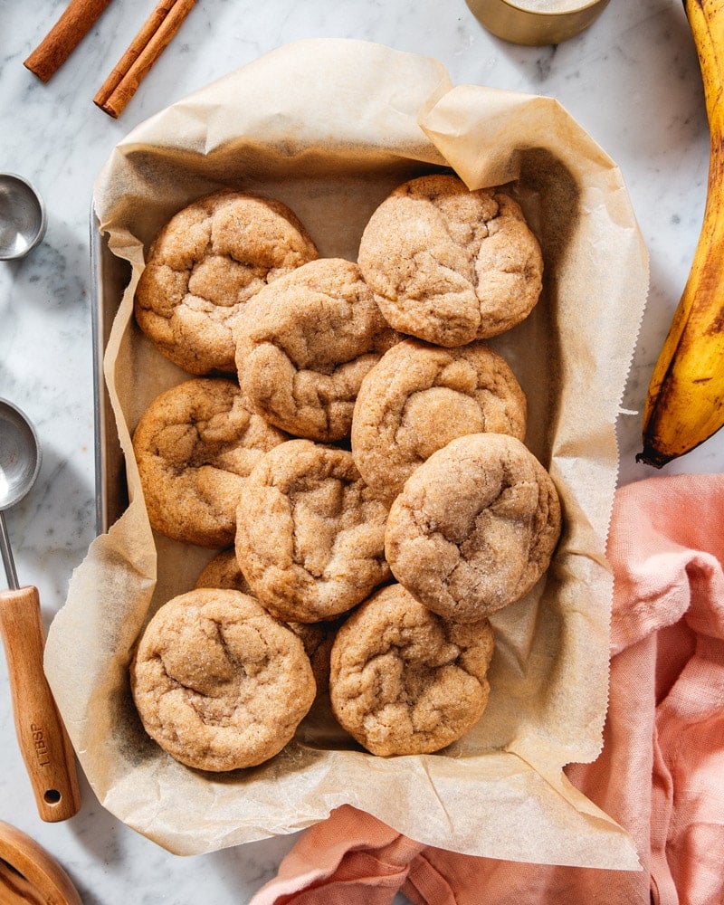 Banana Cookies on a tray with bananas and cinnamon sticks