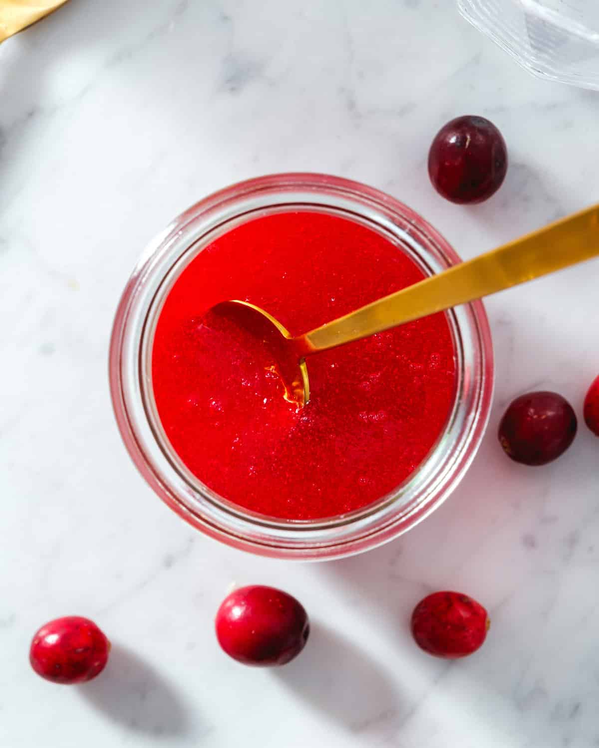 Cranberry Simple Syrup in jar with spoon