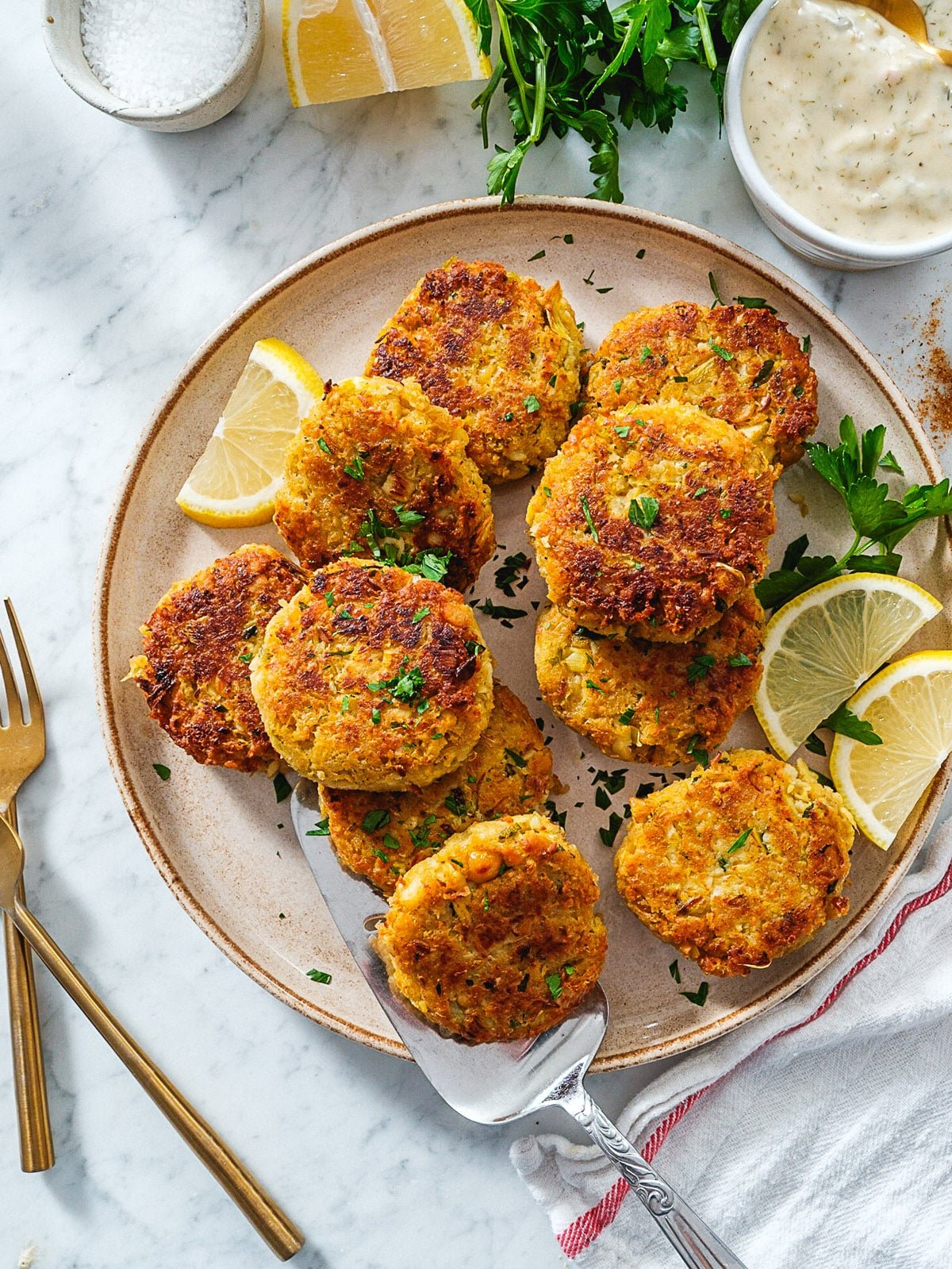 Vegan Crab Cakes on a plate with lemon wedges and a side bowl of Vegan Tartar Sauce