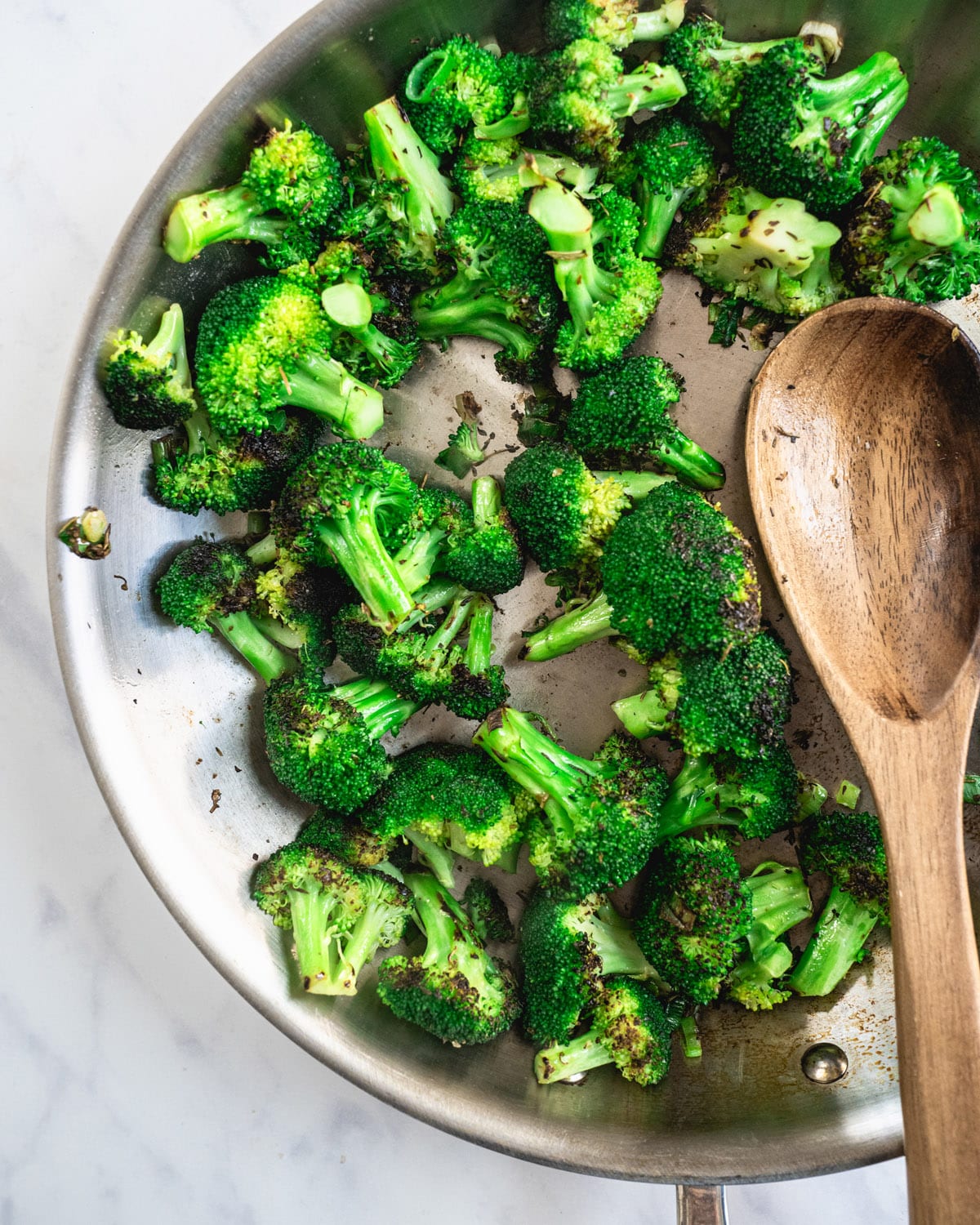 Sauteed broccoli in pan with a wooden spoon