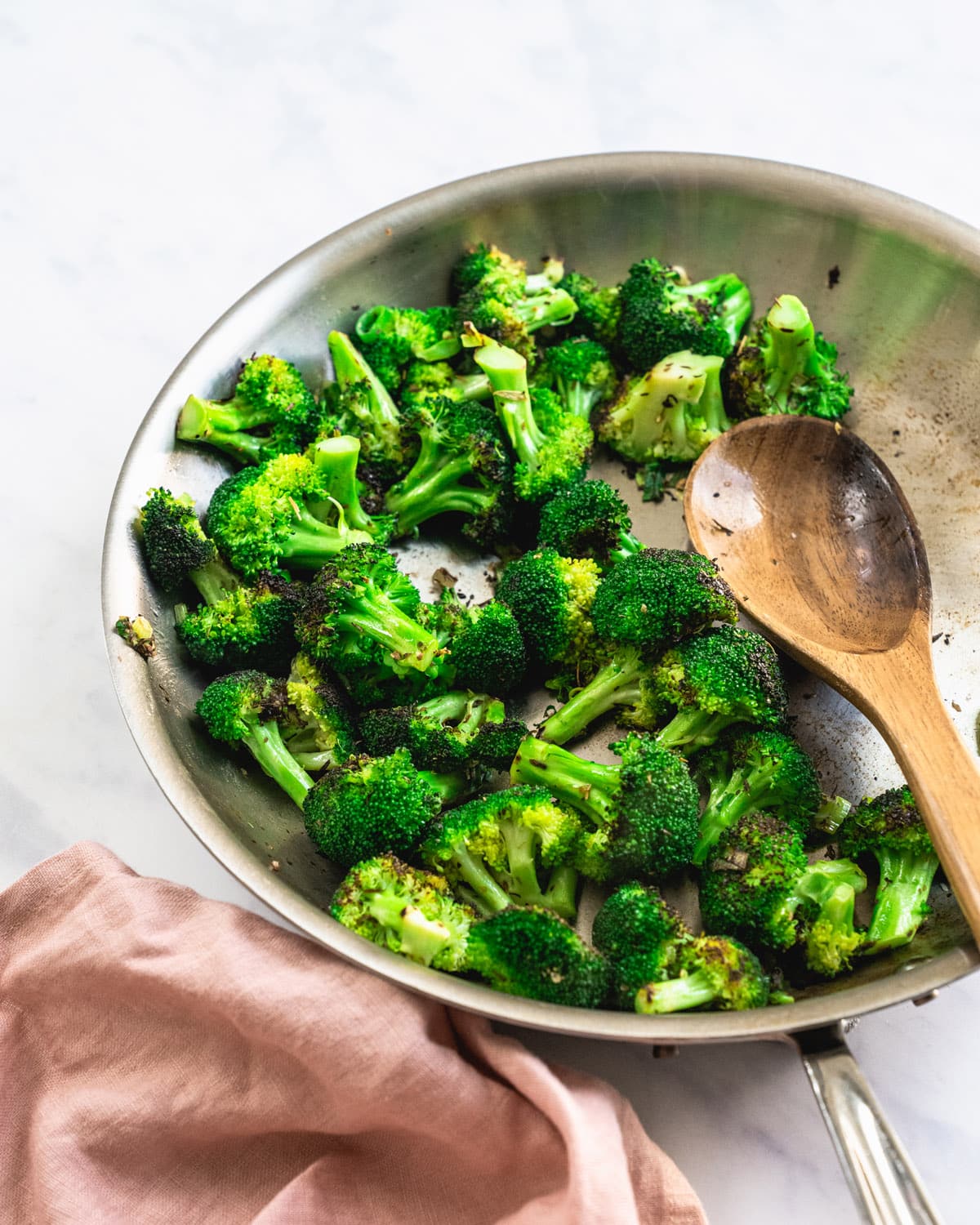 Sauteed broccoli in pan with a wooden spoon