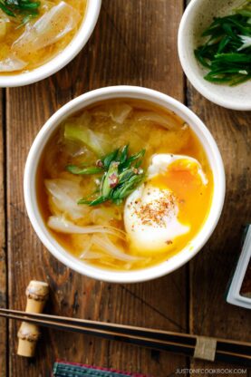 White ceramic bowls containing Cabbage and Onsen Tamago Miso Soup topped with green onions and shichimi togarashi.
