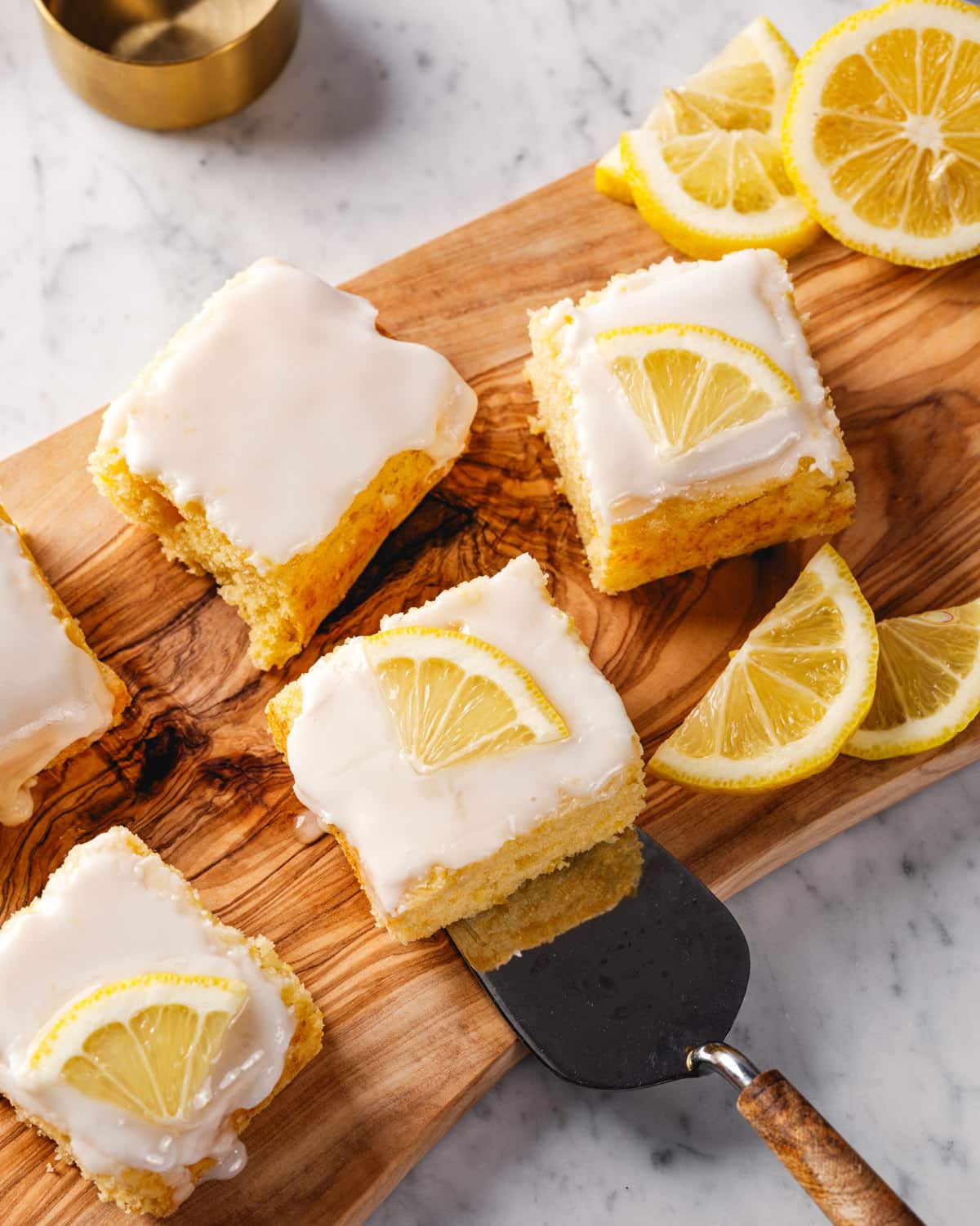 Pieces of Lemon Cake on cake server with lemon slices.