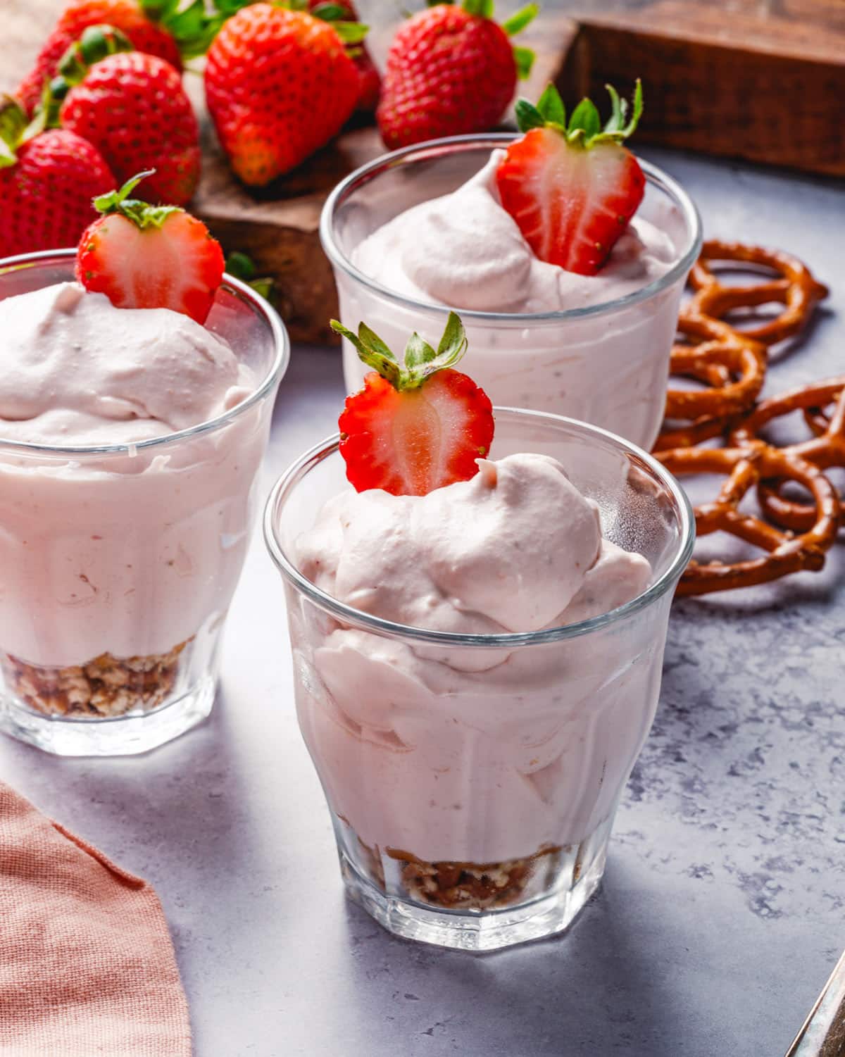 Strawberry Mousse recipe in cups with strawberries and pretzels in background.