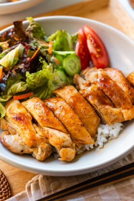 A bowl containing Chicken Teriyaki glazed with homemade teriyaki sauce on the bed of steamed rice.
