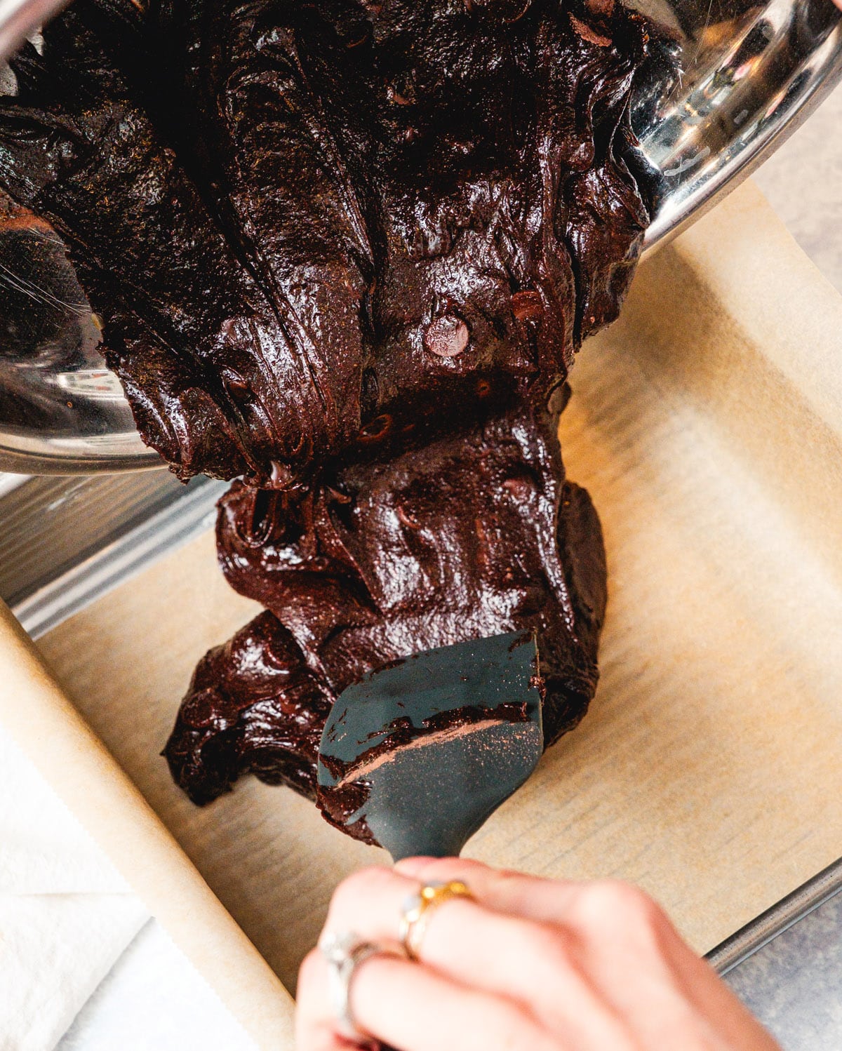 Pouring brownie batter into a prepared pan.