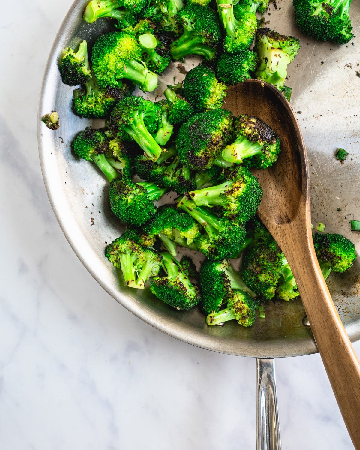 Broccoli being sauteed in a large skillet