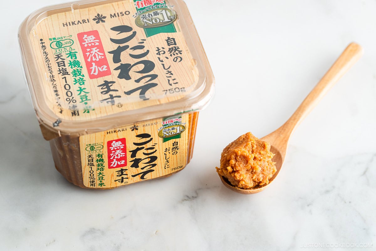Miso in a plastic container with a wooden spoon.