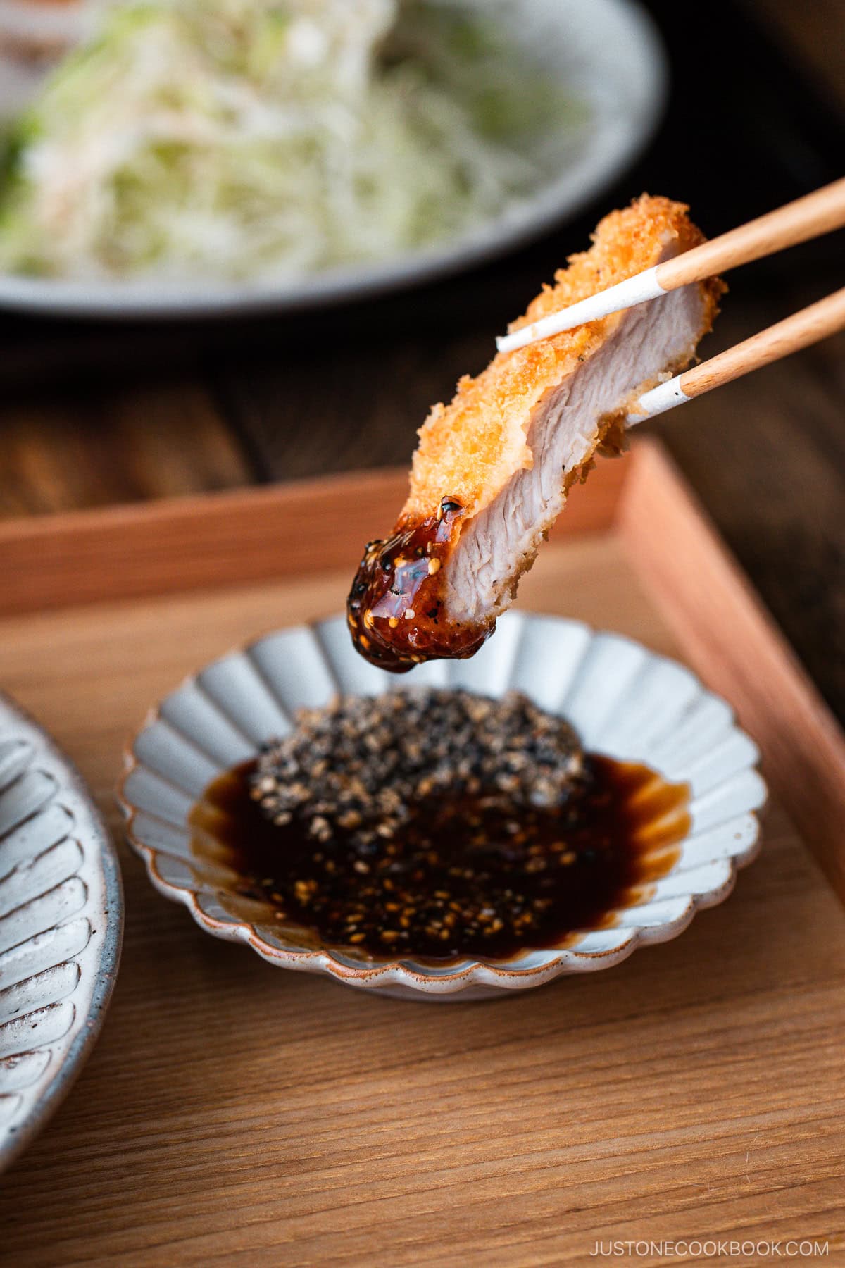 Tonkatsu dipping in the tonkatsu sesame sauce.