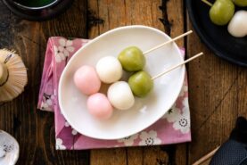 A white oval plate containing two Hanami Dango, served with matcha green tea.