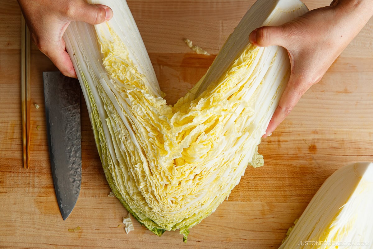 Cut the napa cabbage into quarters and rinse them under water to remove dirt.&nbsp;